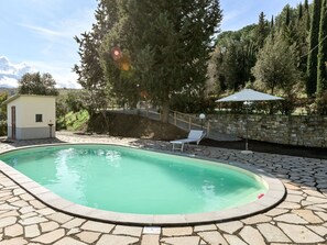Relax by the serene pool surrounded by a stone patio and lush trees.