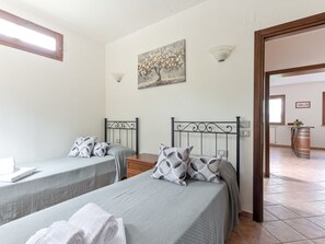 Two single beds with classic metal frames, complemented by a beautiful tree painting above.