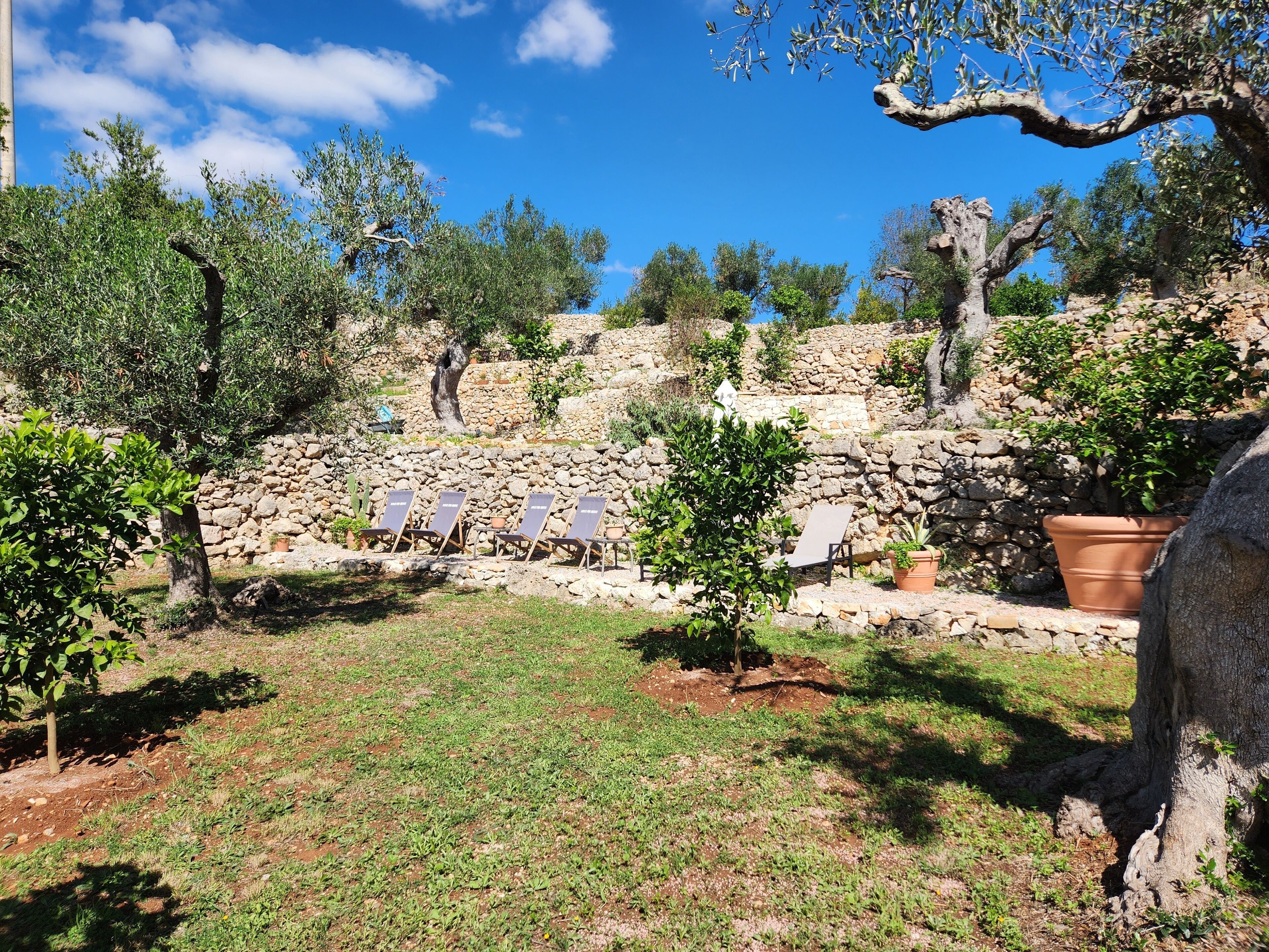 A stone wall with a seating area and potted plants.