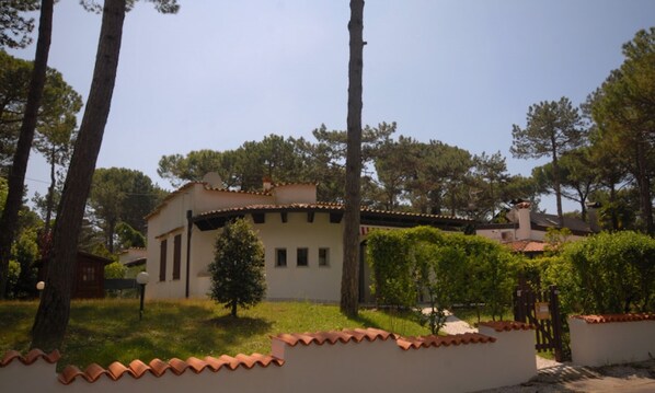 A building with a tiled roof, surrounded by trees and a well-maintained lawn. - Green oasis in Lignano Pineta (Lignano Sabbiadoro)