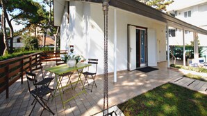Un patio con una mesa y sillas, una lámpara colgante y una puerta que da a un área techada.