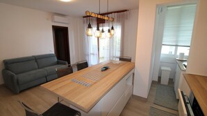 Eine moderne Küche mit Holztischplatte, eingebautem Ofen und einem Essbereich mit grauem Sofa und Tisch.