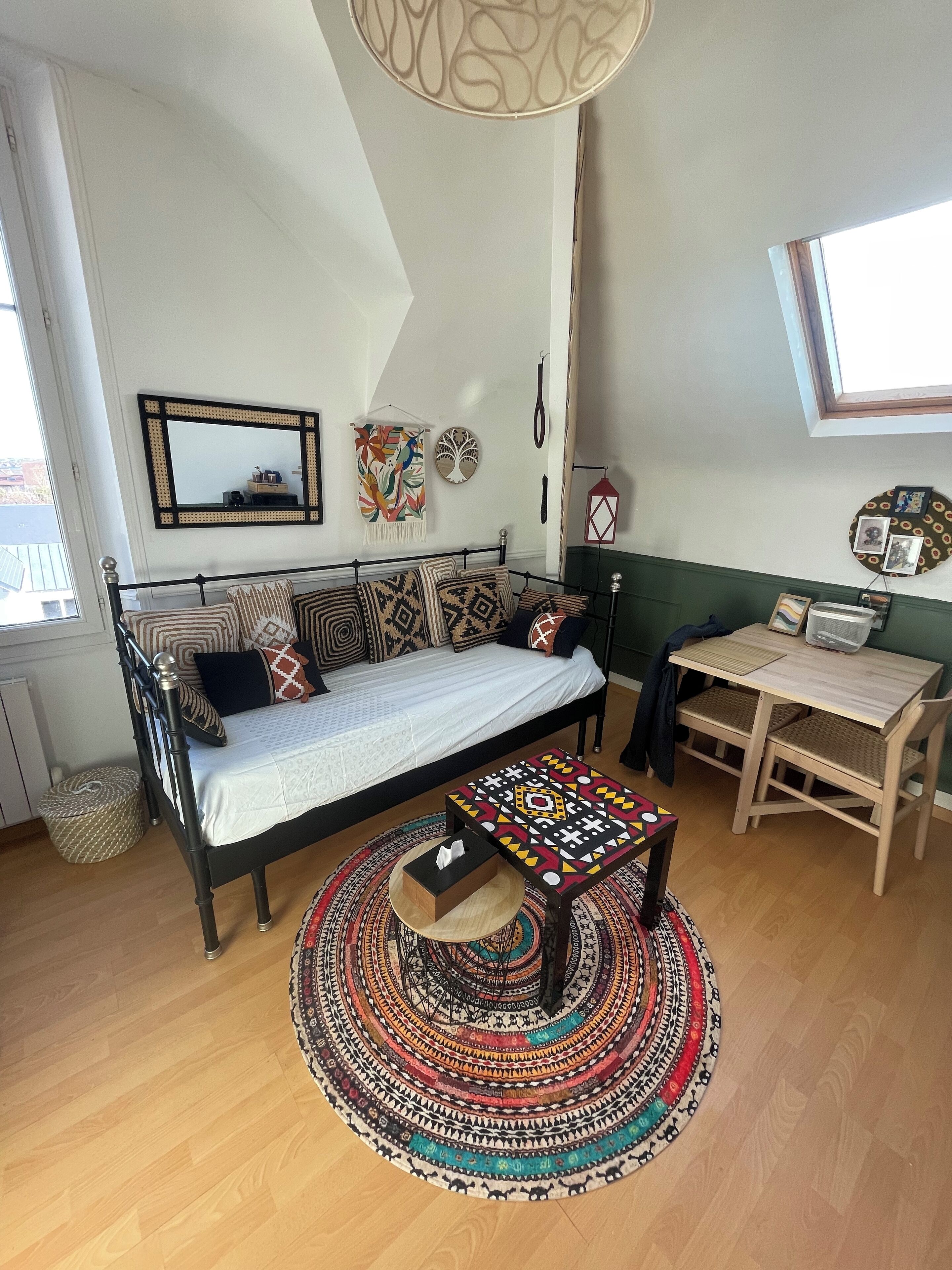 Ein gemütliches Schlafzimmer mit einem Bett, einem kleinen Tisch, einem runden Teppich und einem Fenster.