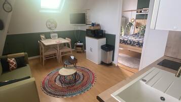 Ett kompakt bostadsutrymme med ett litet kök, en matplats och ett sovrum.