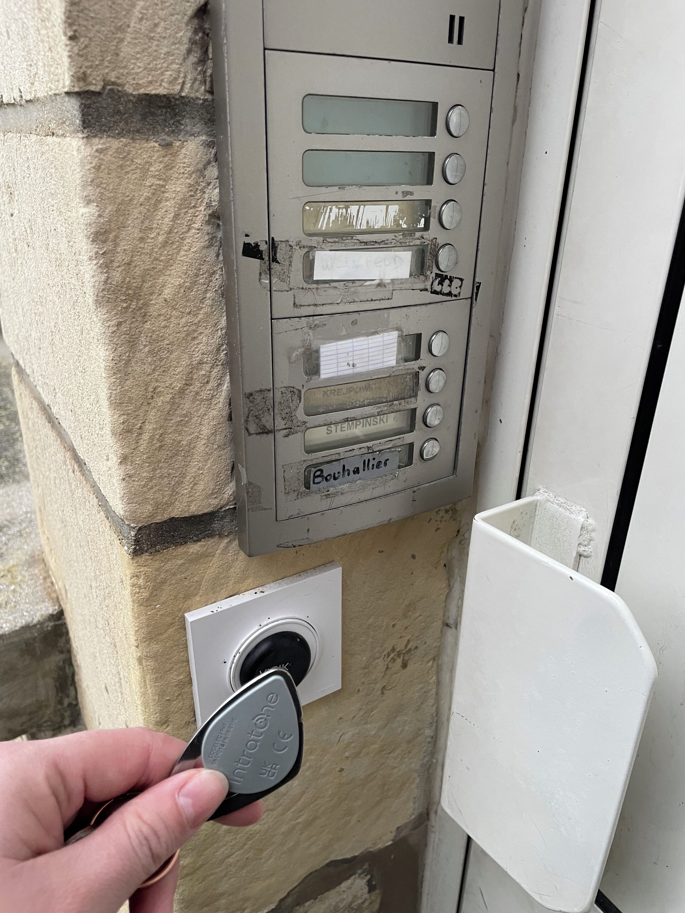 A utility meter box attached to a stone wall with a hand holding a key.