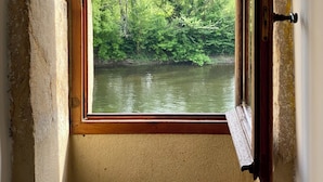 A room with a window overlooking a river and trees.