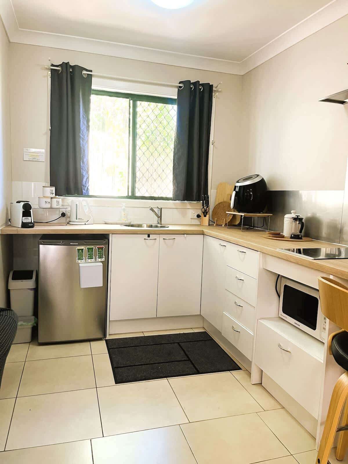 Una cocina compacta equipada con refrigerador, microondas y cafetera.