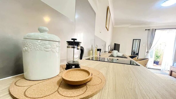 A modern kitchen with a wooden countertop, a white ceramic jar, and a cork mat. - 45 Garden Guest Suite Studio (Bassendean)