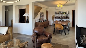 A spacious living room with a leather armchair, a glass coffee table, and a dining area with a wooden table and chairs. - House Pietrosella Sea view 50 m from the beach (Pietrosella)