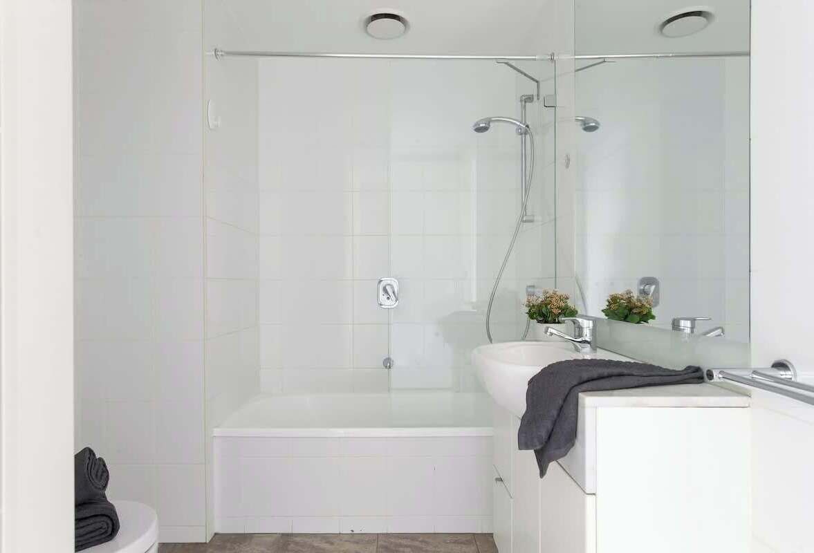 Une salle de bain moderne avec une douche à parois de verre, une baignoire blanche et un meuble-lavabo avec un miroir.