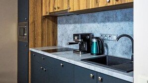 A modern kitchen with dark cabinets, a wooden upper section, a built-in microwave, a coffee machine, and a kettle. - Nice apartment for 2 guests with WIFI, TV and terrace (Jilemnice)