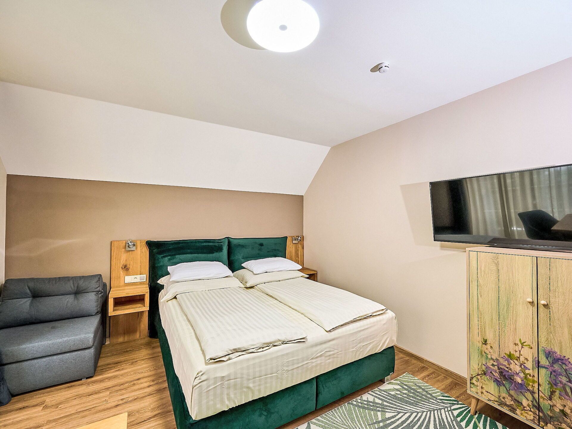 A bedroom with a bed, a chair, a TV, and a cabinet.