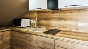 A kitchen with wooden cabinets, a white countertop, a built-in oven, and a sink. - Cosy apartment for 2 people with WIFI, TV and terrace (Jilemnice)