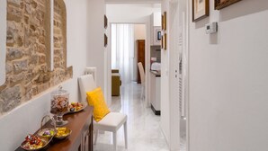 A narrow hallway with a stone wall on one side and a white wall on the other, leading to a kitchen area. - Beautiful apartment for 4 people with A/C, WIFI and TV (Florence)