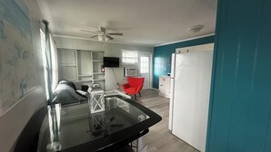 Une cuisine moderne avec un plan de travail noir, une chaise rouge et un réfrigérateur blanc.