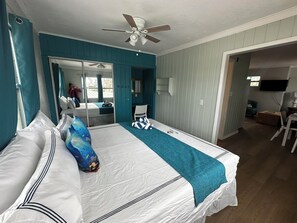 Een slaapkamer met een bed, een plafondventilator, een spiegel en een televisie.