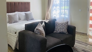 A bedroom with a bed, a sofa, and a window with curtains. - The Residence Hills Lodge (Harare)