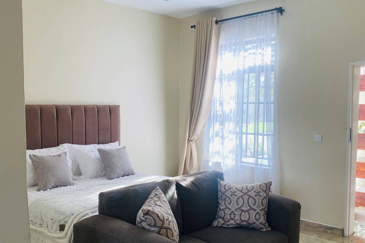 Une chambre à coucher avec un lit, un canapé et une fenêtre avec des rideaux.
