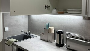 Eine moderne Küche mit integriertem Geschirrspüler, einer Kaffeemaschine und einem Weinglasregal.