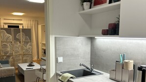 Eine moderne Küche mit integriertem Waschmaschinen, einer Spüle und einem Essbereich inklusive Sofa und Couchtisch.