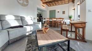 A living room with a sofa, coffee table, and dining area with wooden chairs and a table. - 4 bedroom beautiful home in Neuilly le Vendin (Neuilly le Vendin)