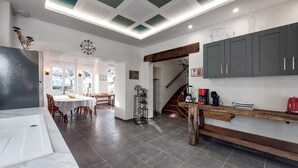A modern kitchen with dark tiles, a wooden dining table, and a staircase leading to another level. - 4 bedroom beautiful home in Neuilly le Vendin (Neuilly le Vendin)