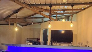 Un espace bar avec un comptoir illuminé de lumière bleue, plusieurs tabourets et des luminaires suspendus.