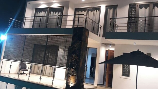 Une maison moderne à deux étages, dotée d’un balcon, d’une piscine et d’un espace salon extérieur.