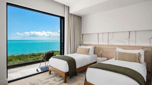 Une chambre moderne avec deux lits, une grande fenêtre donnant sur l’océan et un design minimaliste.