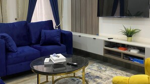 A modern living room with a blue sofa, a round coffee table, and a yellow armchair. - Stylishly decorated 2-bedroom apartment in a serene lovely environment (Lagos)