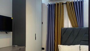 A modern bedroom with a bed, a TV, a wardrobe, and an air conditioning unit. - Stylishly decorated 2-bedroom apartment in a serene lovely environment (Lagos)
