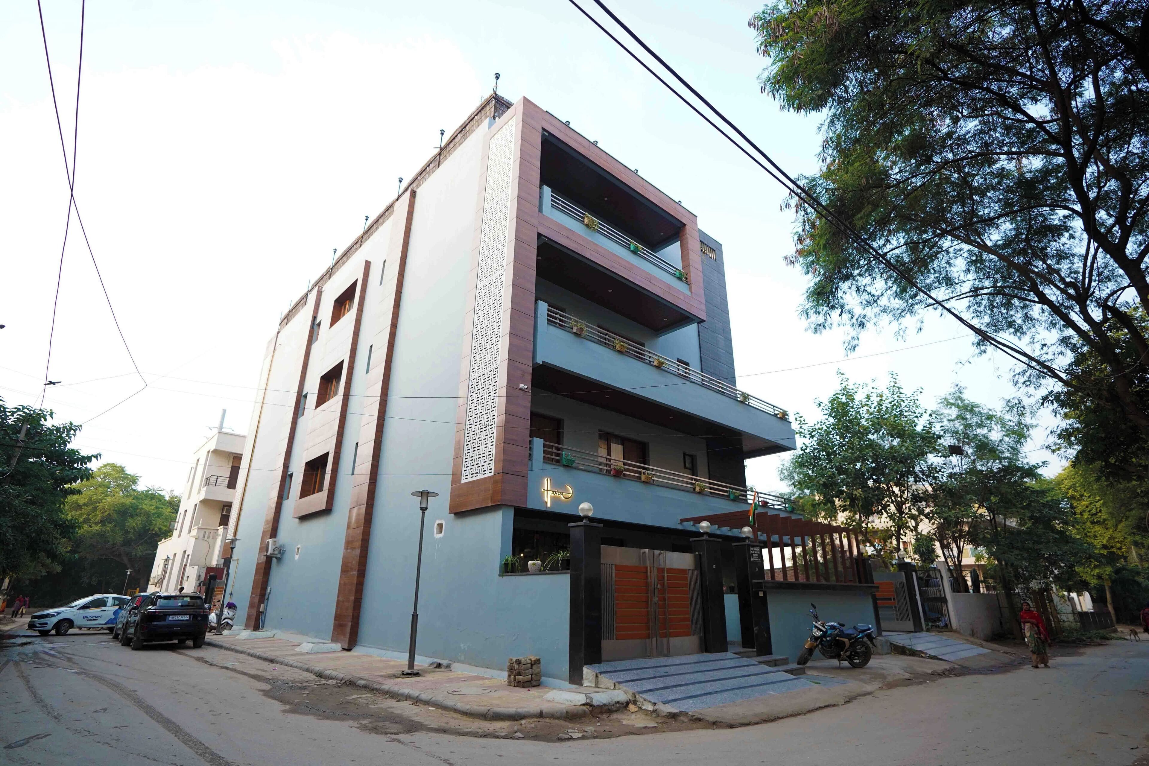A multi-story building with a flat roof, a gated entrance, and a staircase leading to the entrance.