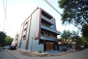 A multi-story building with a flat roof, a gated entrance, and a staircase leading to the entrance. - Haven Hotel Sector 31,Gurugram (Gurugram)