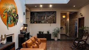 A modern living room with a leather sofa, a fireplace, and a large wall mural. - Haven Hotel Sector 31,Gurugram (Gurugram)