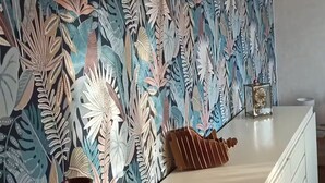 Une pièce avec un meuble blanc et un mur décoratif orné d’un motif de feuilles.
