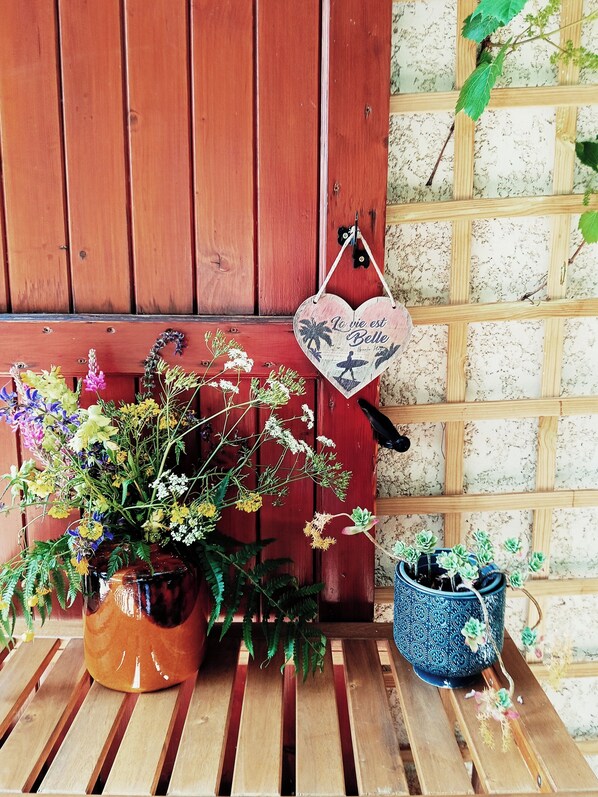 A wooden bench with a potted plant and a hanging heart-shaped decoration.
