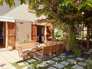 En uteplats med trädgårdsmöbler, en pergola och krukväxter.