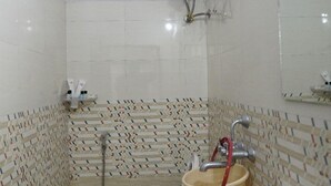 A bathroom with a toilet, bidet, and sink, tiled walls, and a window. - hotel cozy (Hyderabad)