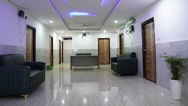 A modern lobby with a marble floor, dark sofas, a central bench, and wooden doors. - hotel cozy (Hyderabad)