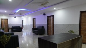 A modern hotel lobby with a marble floor, black sofas, a wooden reception desk, and a ceiling fan. - hotel cozy (Hyderabad)