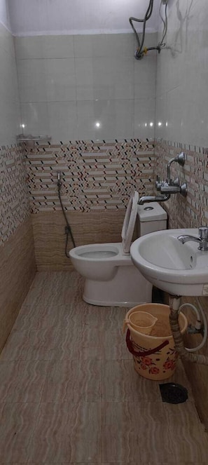 A bathroom with a toilet, sink, and shower. - hotel cozy (Hyderabad)