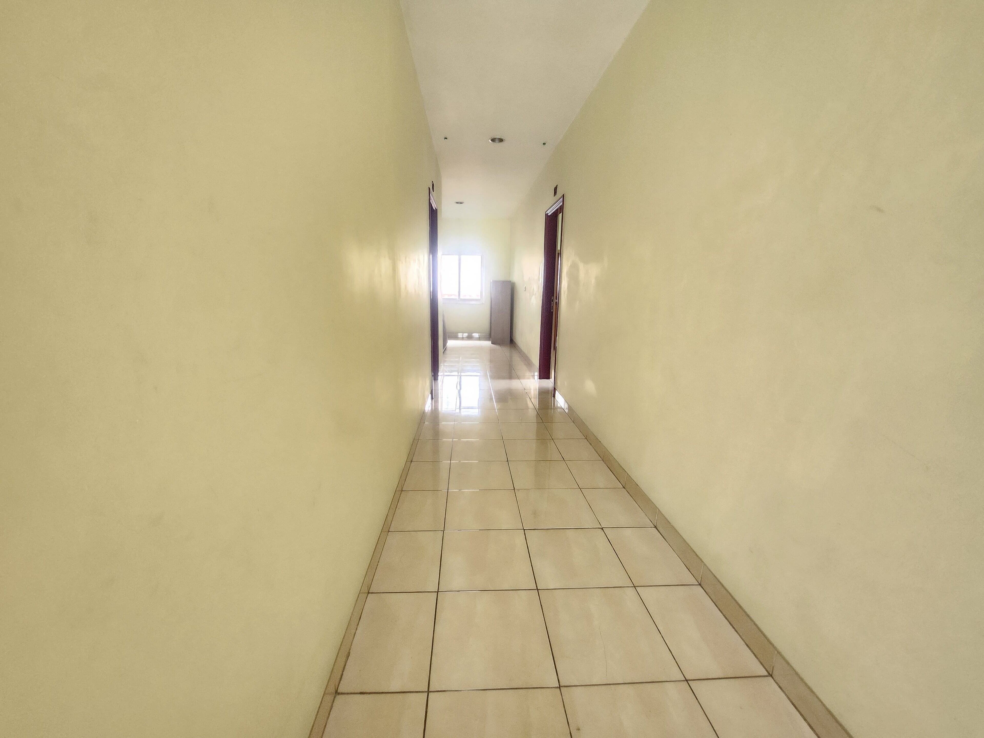A long, narrow hallway with tiled floors and plain walls.