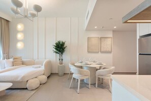 A modern hotel room with a bed, a dining table with chairs, a potted plant, and a kitchen area. - Bright and Exquisite 1-Bedroom in Downtown views 2 (Dubai)