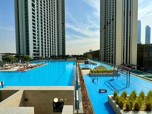 A rooftop swimming pool with lounge chairs and a small play area, surrounded by high-rise buildings.