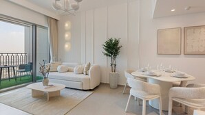 Una sala de estar moderna con un sofá, una mesa de centro, una mesa de comedor y sillas. Hay una planta en maceta y obras de arte en las paredes.