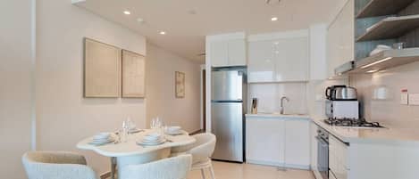 A modern kitchen with white cabinetry, a built-in stove, and a refrigerator.