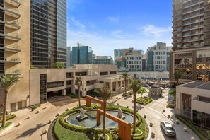 A modern urban complex with multiple high-rise buildings, a central courtyard with a fountain, and a parking area.