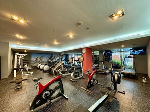 A gym with various exercise equipment, including treadmills, stationary bikes, and weight machines. - Exquisite and Capacious 1BR in South Ridge 3 (Dubai)