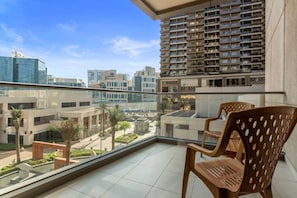 A balcony with a view of a cityscape, featuring modern buildings and a clear sky.
