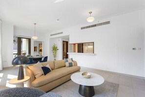 A modern living room with a sofa, a round coffee table, and pendant lighting. - Exquisite and Capacious 1BR in South Ridge 3 (Dubai)